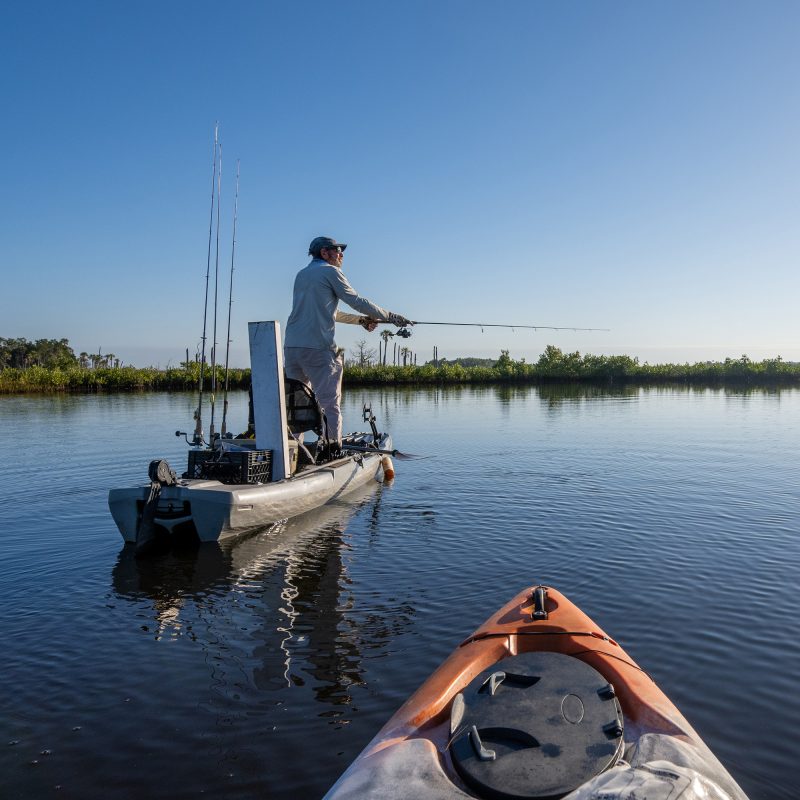 Angler fishing from a kayak in calm waters surrounded by nature